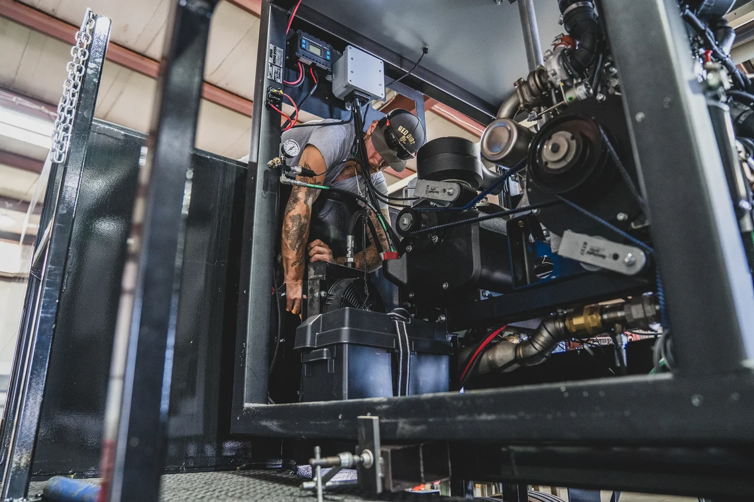 Technician servicing the pump and engine inside the open frame of a Knight Fire trailer-mounted unit