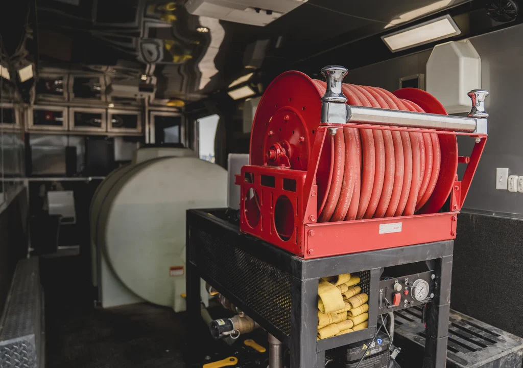 Red hose reel and control panel inside a Knight Fire fire suppression system mounted on a fire engine, with foam tank and equipment storage visible.